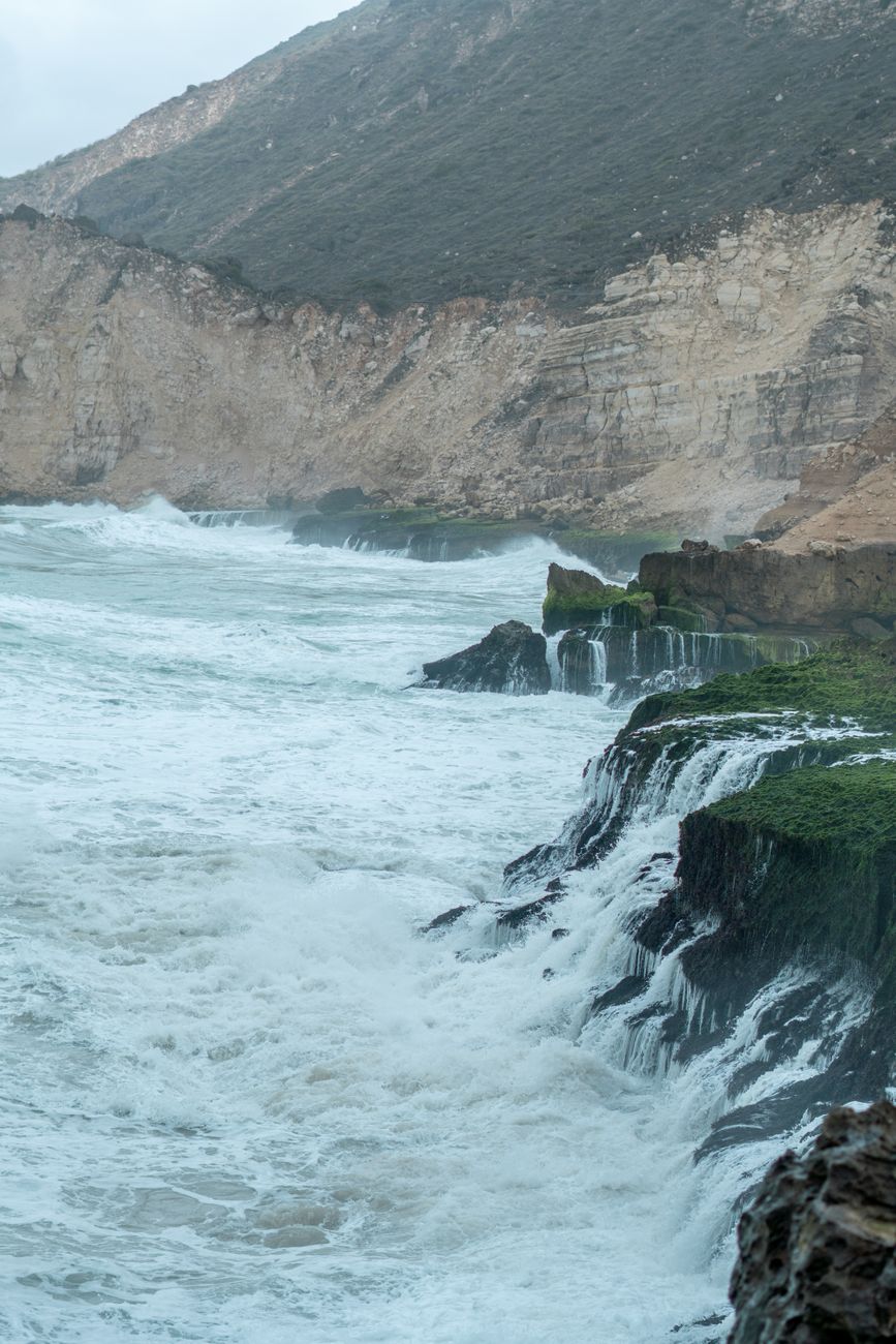 Pacific Ocean waves crashing against rocky Big Sur coastline at dusk
